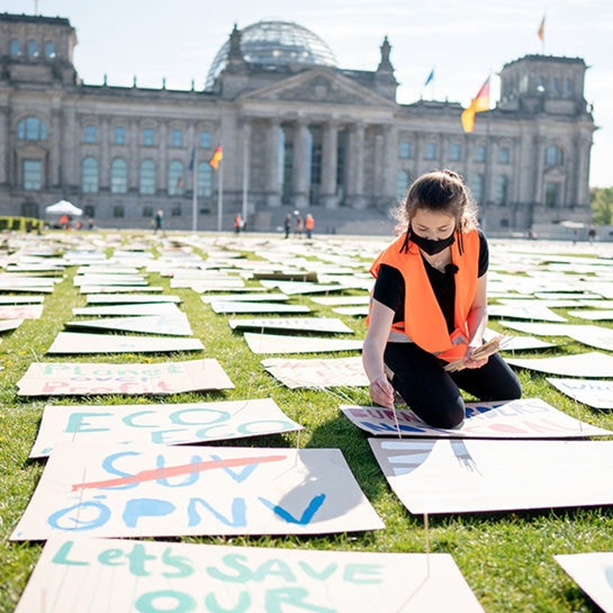 A climate activist and protest signs in front of the german parliament.